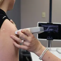 Wykonanie USG barku, kluczowe dla diagnostyki stożka rotatorów. Obraz na monitorze pokazuje strukturę mięśni.