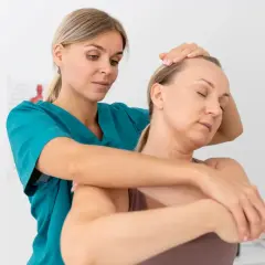 Fizjoterapeutka wykonuje masaż szyi pacjentki, stosując metody neurofizjologiczne.